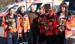 Wolfgang Maxeiner von der DRK-Rettungsdienst Rhein-Main-Taunus GmbH übergibt rote Rosen als Dankeschön für den starken Einsatz der starken Frauen.