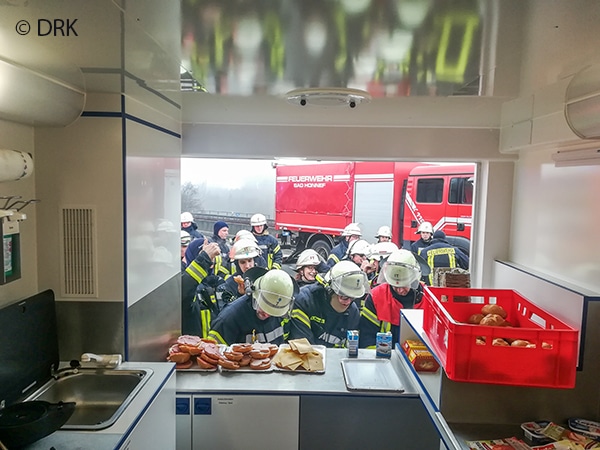 Feuerwehrleute bei der Speisen- und Getränkeausgabe am GW Verpflegung